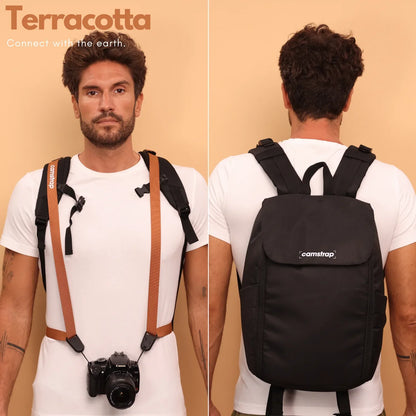 Camstrap Nomad 20L hands-free photography backpack worn on one shoulder with a DSLR clipped to the strap.