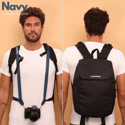 Camstrap Nomad 20L hands-free photography backpack worn on one shoulder with a DSLR clipped to the strap.