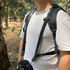 Man with sunglasses and camera equipment standing in a forested area